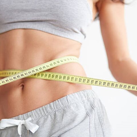 Slim girl with centimeter on white. Closeup woman measuring her waist with tape. Weight loss concept