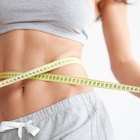 Slim girl with centimeter on white. Closeup woman measuring her waist with tape. Weight loss concept